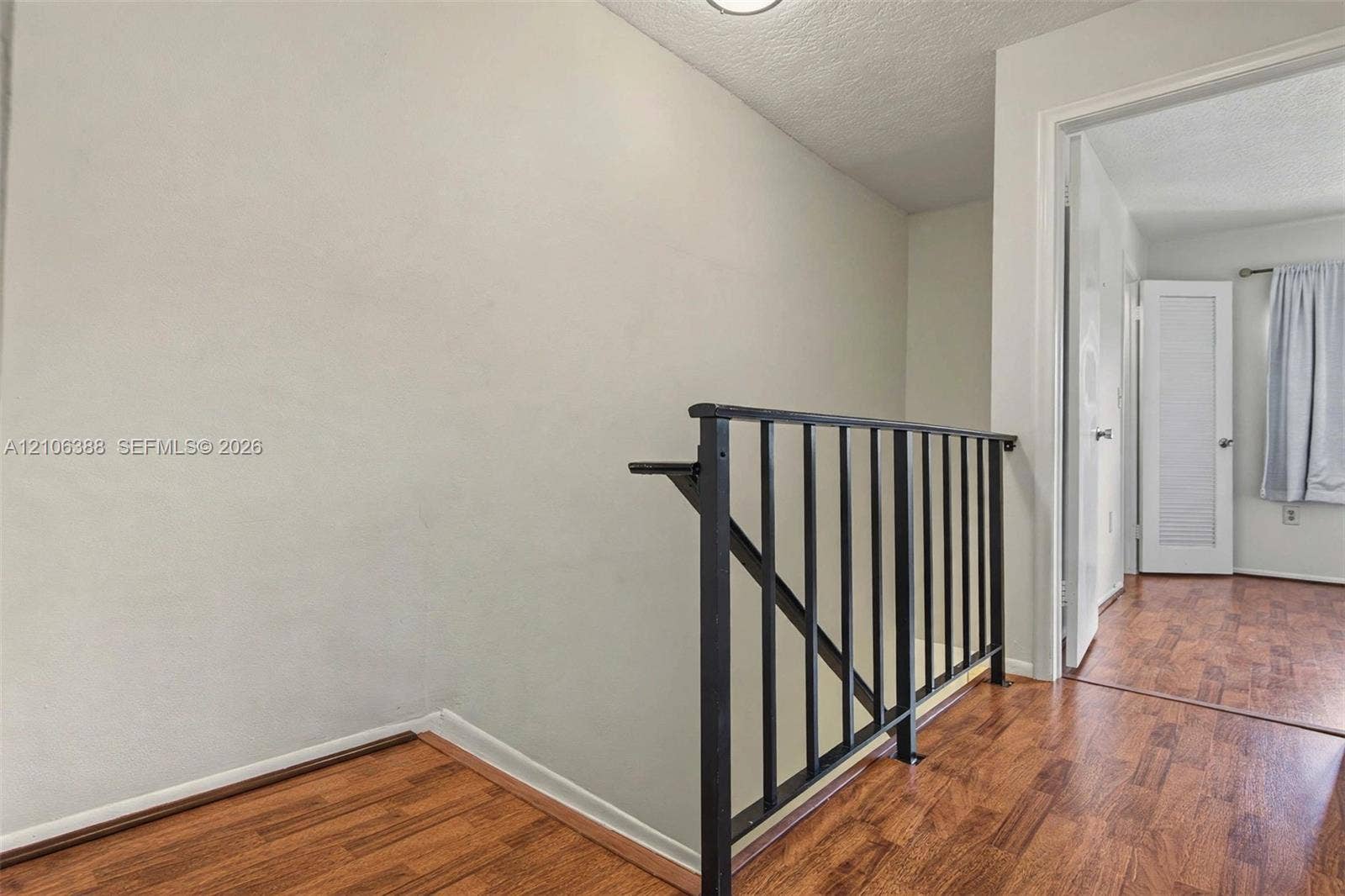 8110 SW 82nd Court, Miami, FL 33143 Wood-finish flooring featuring a black metal balustrade and a louvered panel door