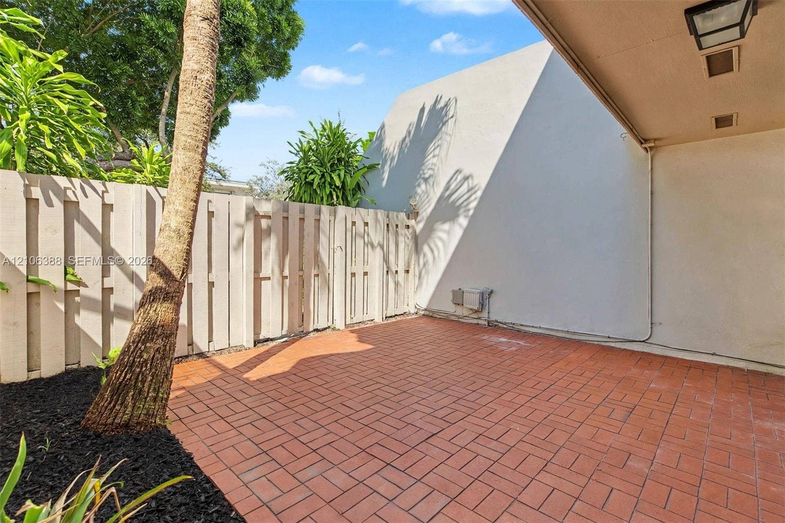 8110 SW 82nd Court, Miami, FL 33143 Private patio featuring red brick paving, a covered overhang with recessed lighting, and a solid wood privacy fence