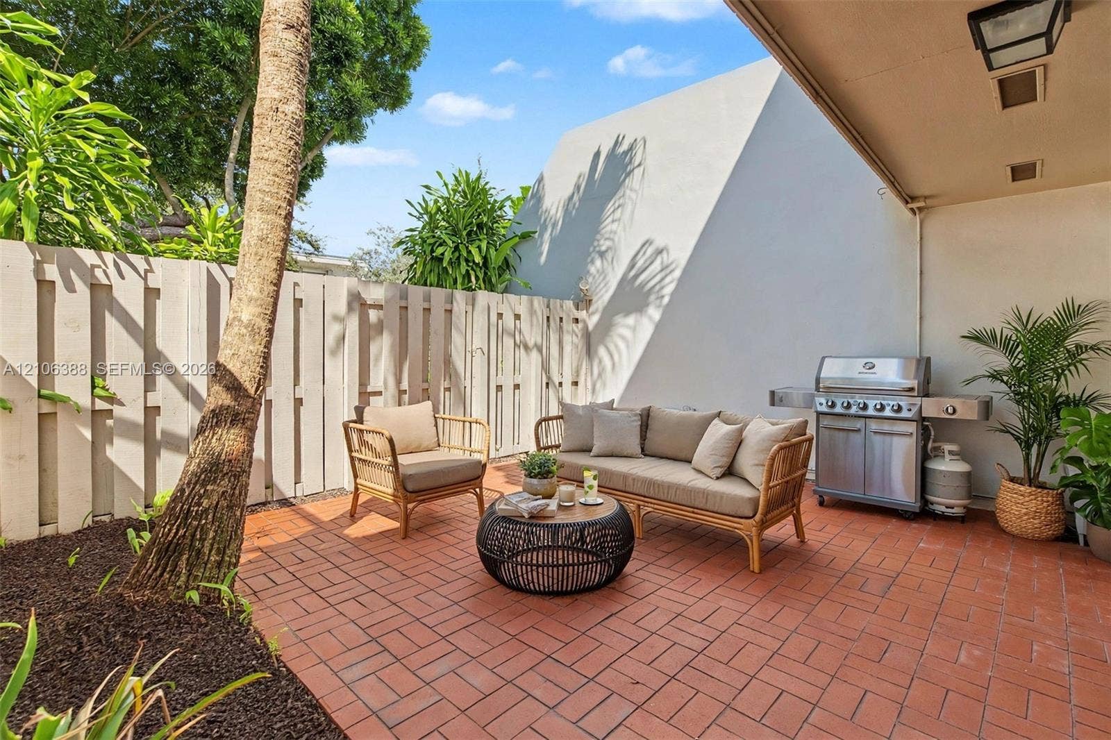 8110 SW 82nd Court, Miami, FL 33143 Covered patio featuring red brick paving, a built-in stainless steel outdoor grill, and a solid perimeter privacy fence