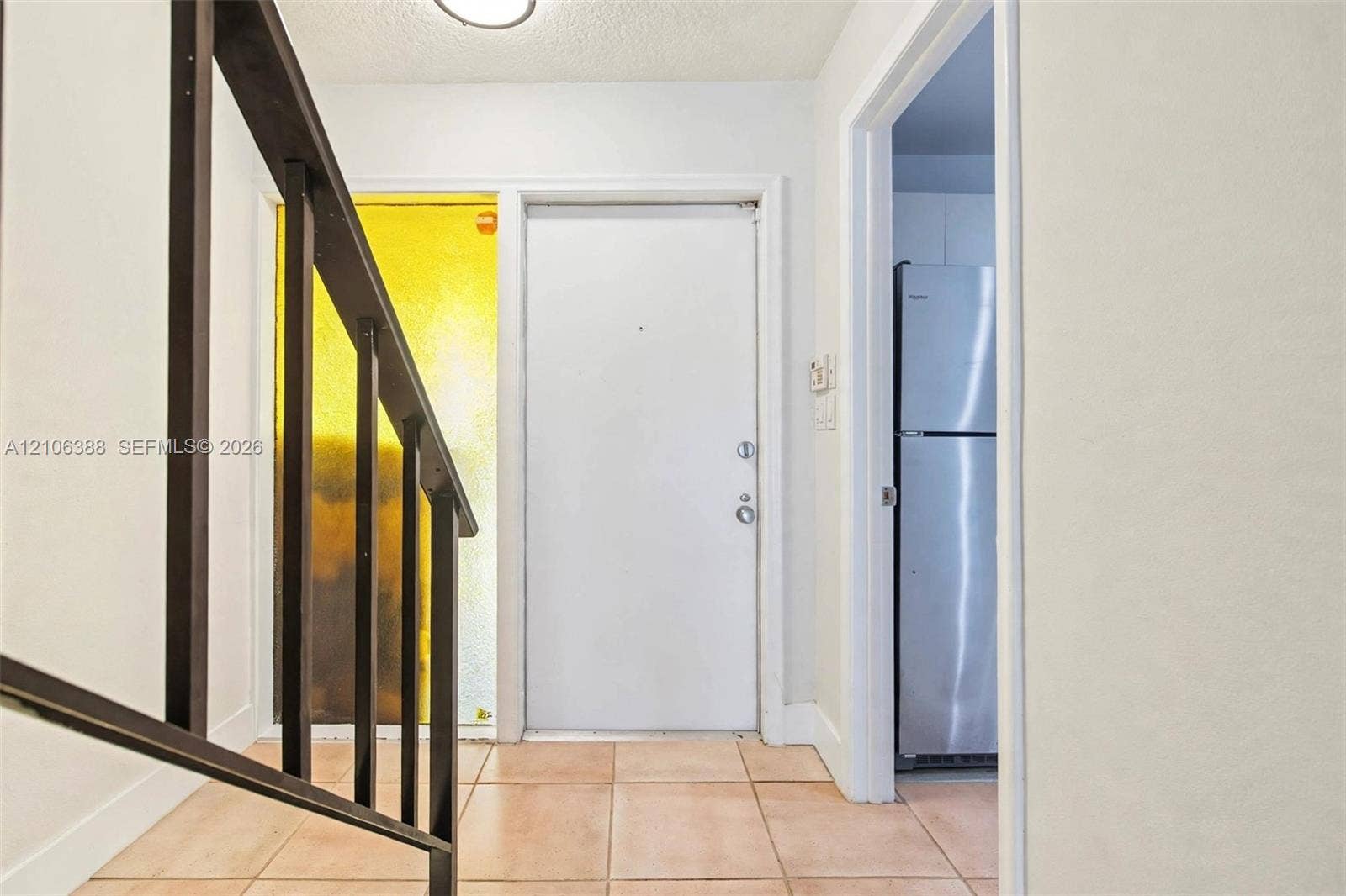 8110 SW 82nd Court, Miami, FL 33143 Entryway featuring tile flooring, a staircase with a dark-toned metal railing, a solid core entry door, and a textured glass sidelight