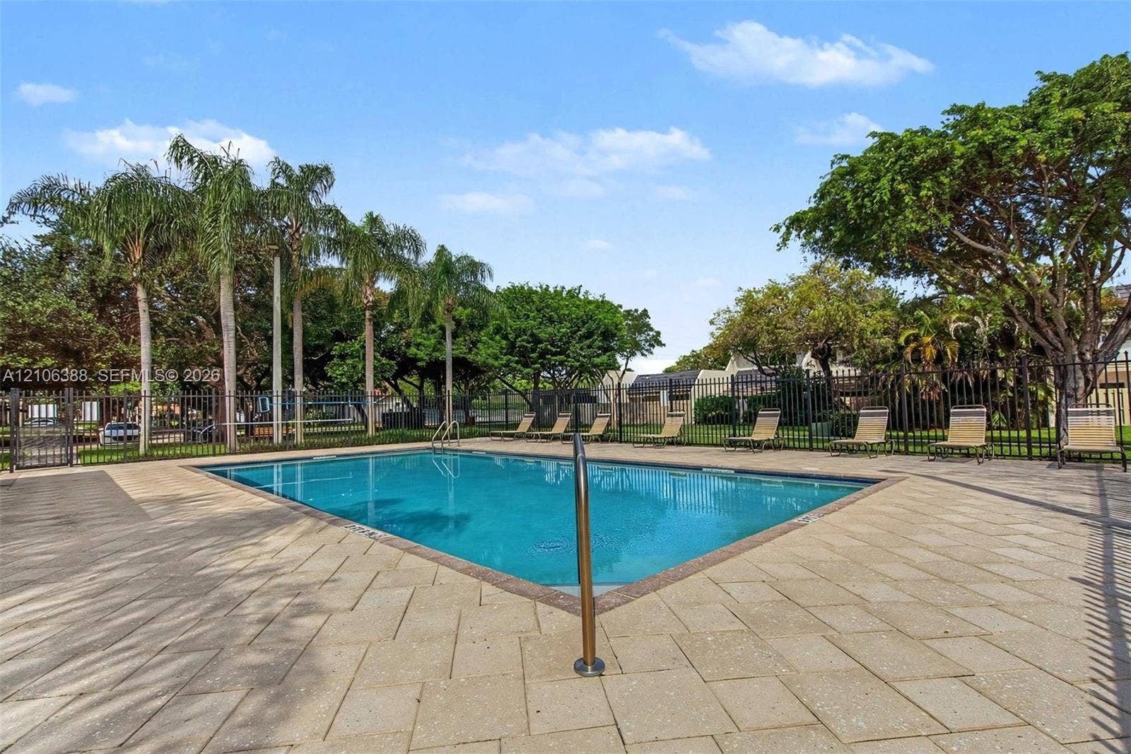 8110 SW 82nd Court, Miami, FL 33143 Outdoor swimming pool featuring a paved pool deck, metal perimeter fencing, and mature palm trees