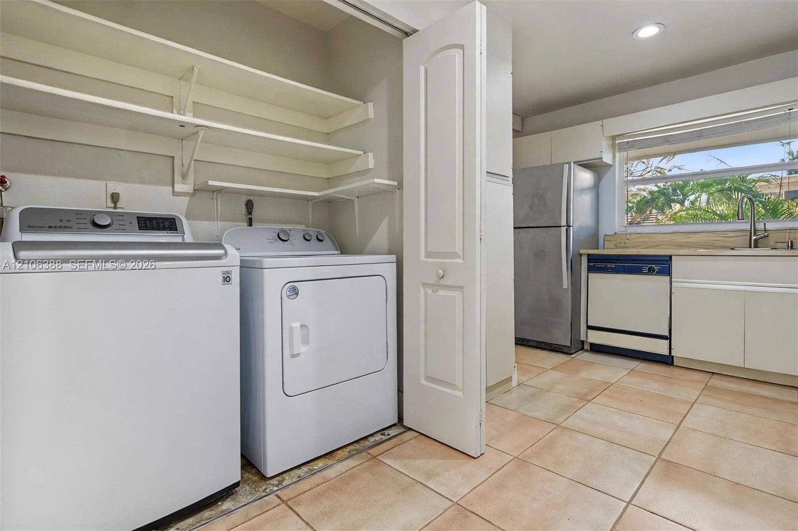 8110 SW 82nd Court, Miami, FL 33143 Laundry area featuring open wall-mounted shelving and tile flooring, with built-in cabinetry, stainless steel refrigerator, and integrated dishwasher