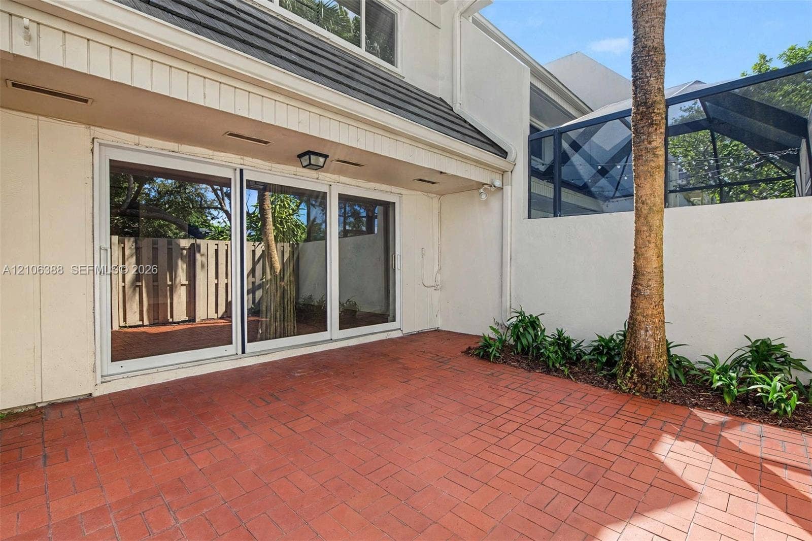 8110 SW 82nd Court, Miami, FL 33143 Private courtyard featuring brick paver flooring, sliding glass doors, a screened-in enclosure, and mature palm landscaping