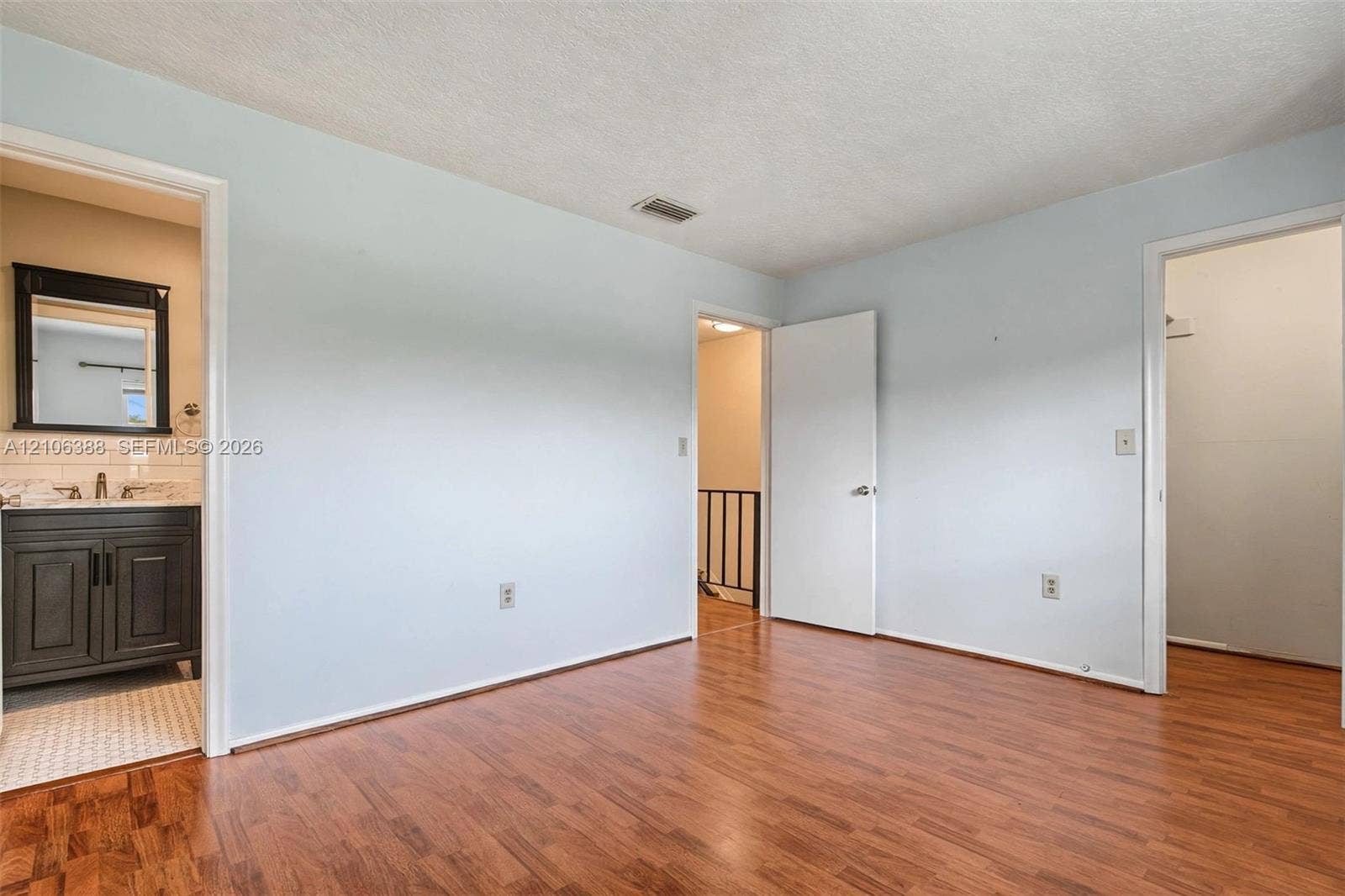 8110 SW 82nd Court, Miami, FL 33143 Interior space featuring wood-finish flooring, two interior doors, and a vanity area with built-in cabinetry and wall-mounted mirror