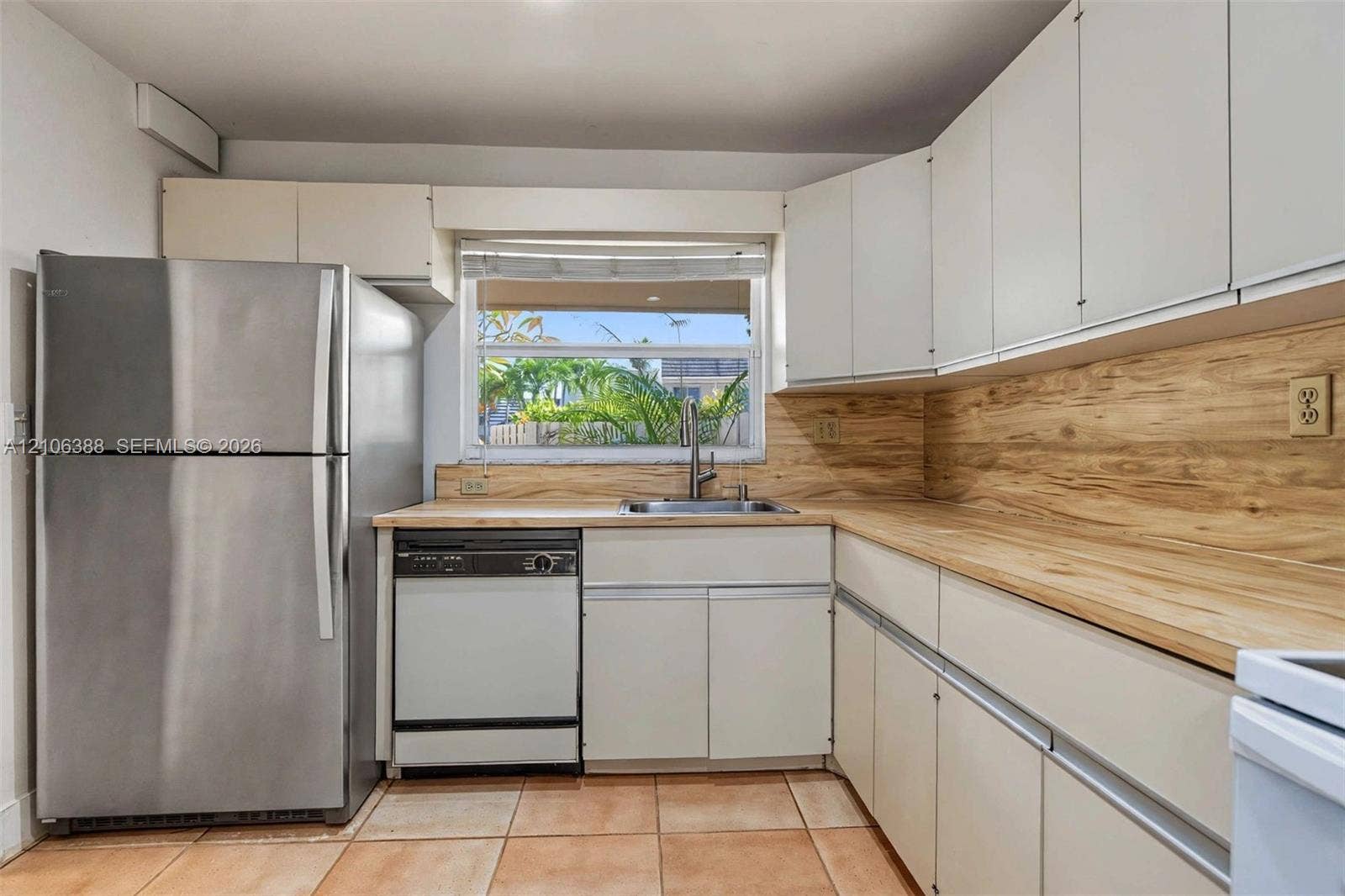 8110 SW 82nd Court, Miami, FL 33143 Kitchen featuring flat-panel cabinetry, light wood-finish countertops with matching backsplash, stainless steel refrigerator, stainless steel dishwasher, and ceramic tile flooring