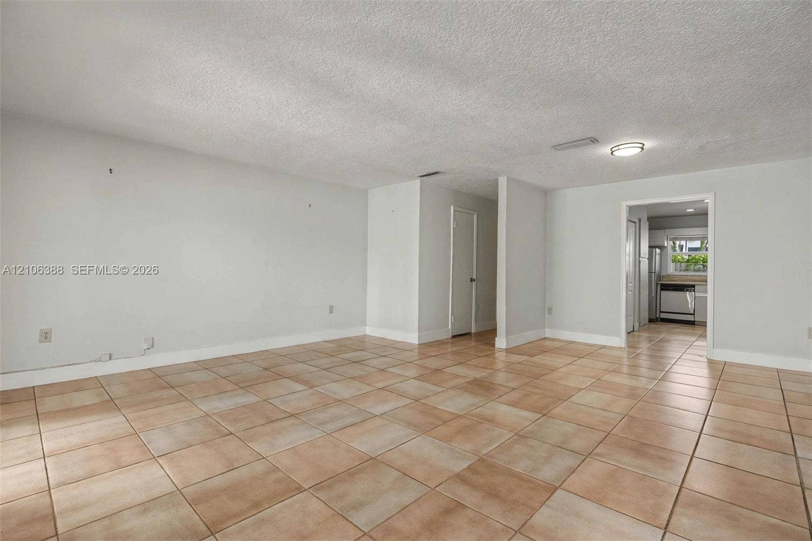 8110 SW 82nd Court, Miami, FL 33143 Neutral-toned interior space featuring light-colored ceramic tile flooring, a textured ceiling, and a flush-mount light fixture