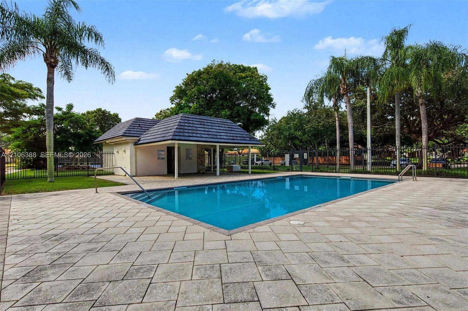 8110 SW 82nd Court, Miami, FL 33143 In-ground rectangular swimming pool featuring a tiled deck, metal handrails, and a nearby covered pavilion with a hipped roof