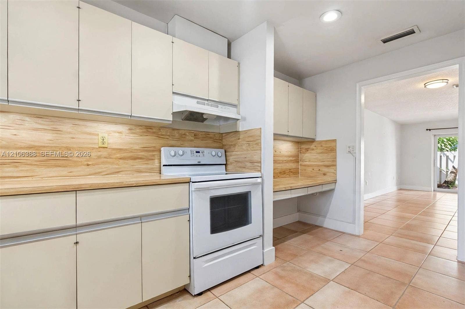 8110 SW 82nd Court, Miami, FL 33143 Kitchen featuring flat-panel cabinetry, light-toned wood-finish backsplash, integrated range hood, tile flooring, and built-in workstation