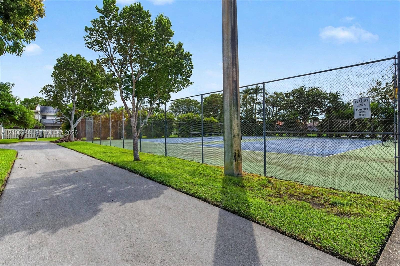 8110 SW 82nd Court, Miami, FL 33143 Outdoor recreational area featuring a paved pathway, tennis court with chain-link fencing, and manicured green space