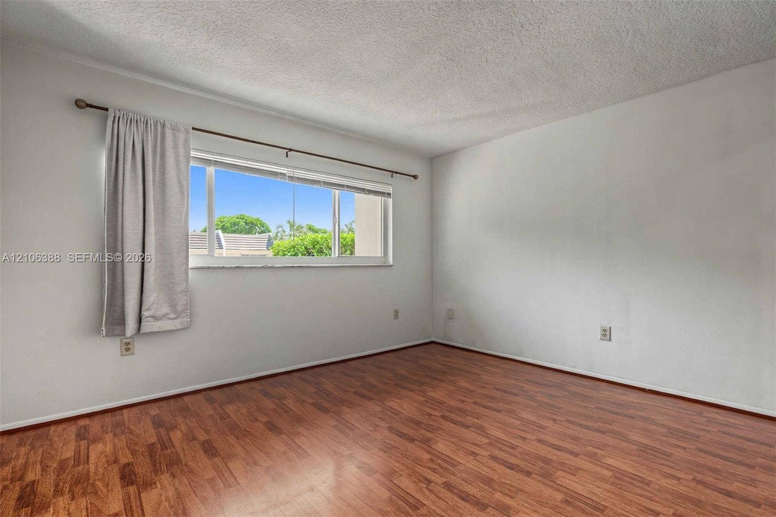 8110 SW 82nd Court, Miami, FL 33143 Interior room featuring wood-finish flooring, a multi-pane horizontal window, and a textured ceiling