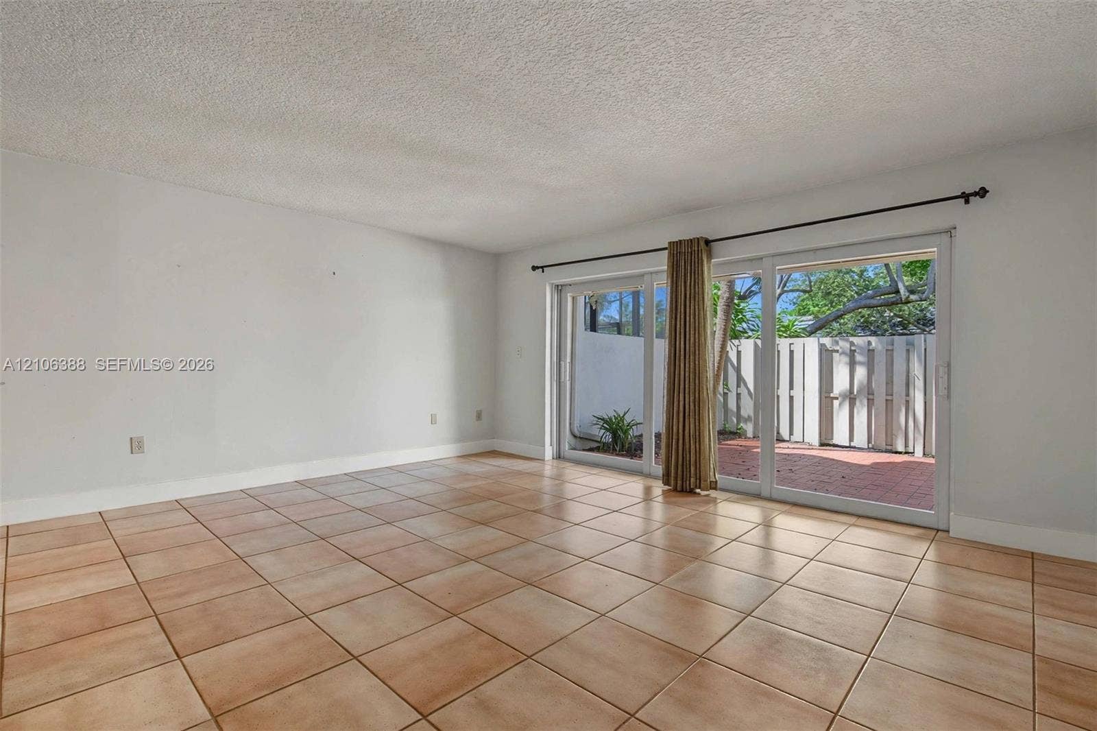 8110 SW 82nd Court, Miami, FL 33143 Spacious room featuring large-format square tile flooring, neutral wall tones, and glass sliding doors