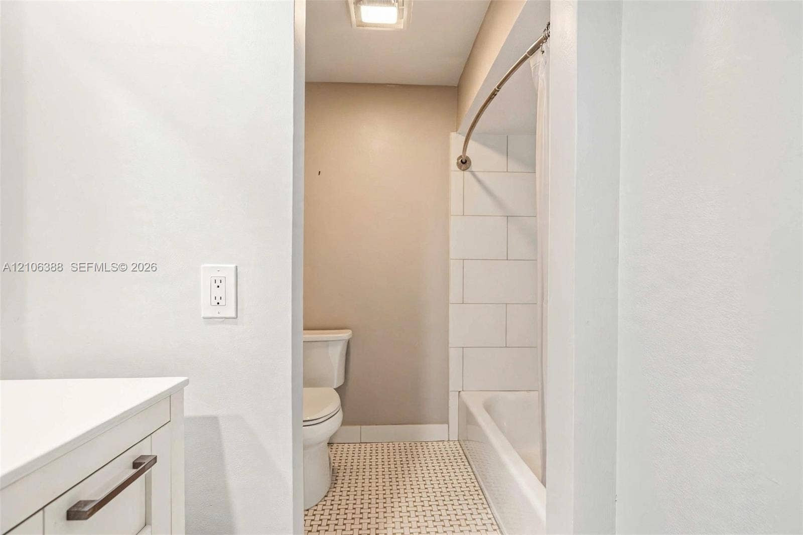 8110 SW 82nd Court, Miami, FL 33143 Bathroom featuring a white vanity, a tiled bathtub surround, a curved shower rod, and patterned tile flooring