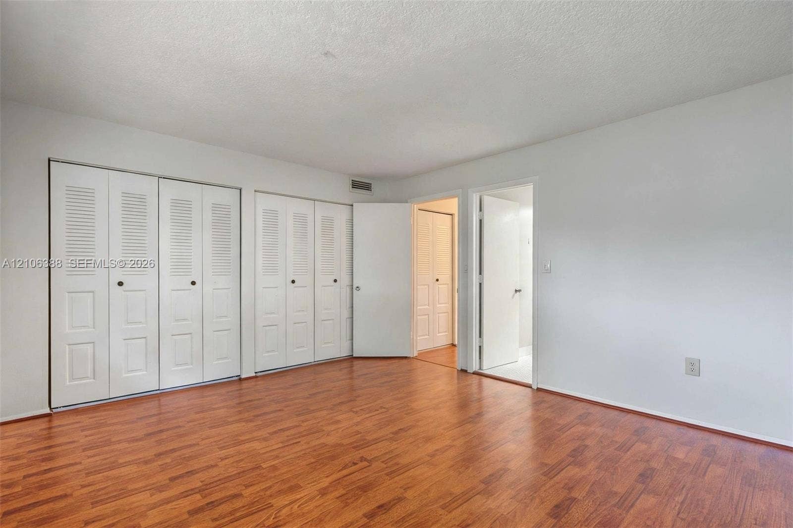 8110 SW 82nd Court, Miami, FL 33143 Room featuring wood-finish flooring, multiple sets of white bi-fold closet doors, and solid-core interior doors