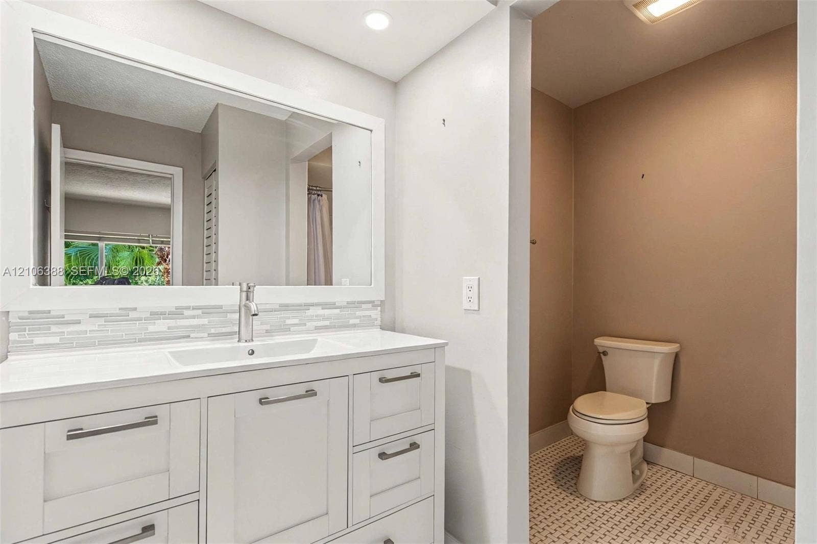 8110 SW 82nd Court, Miami, FL 33143 White shaker-style cabinetry with a smooth surface countertop, rectangular integrated basin, decorative glass tile backsplash, and oversized wall-mounted mirror