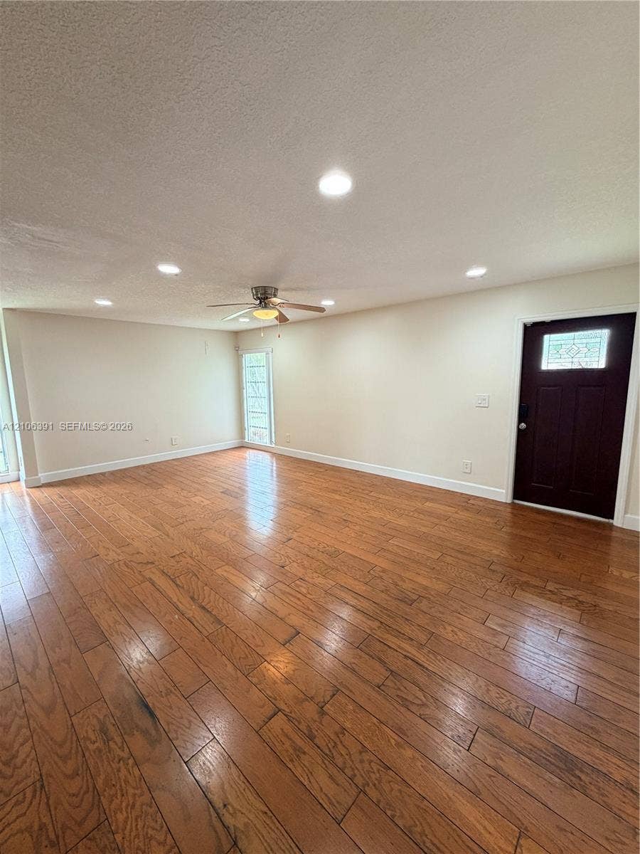 Wood-finish flooring, recessed lighting, ceiling fan, and an exterior door featuring an inset glass panel