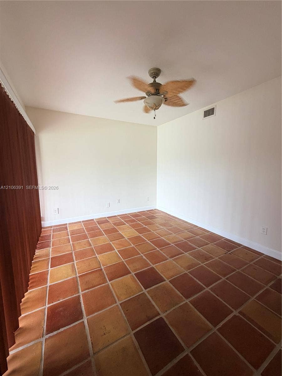 Interior room featuring square terra-cotta tile flooring, vaulted ceilings, and a ceiling fan with integrated light fixture