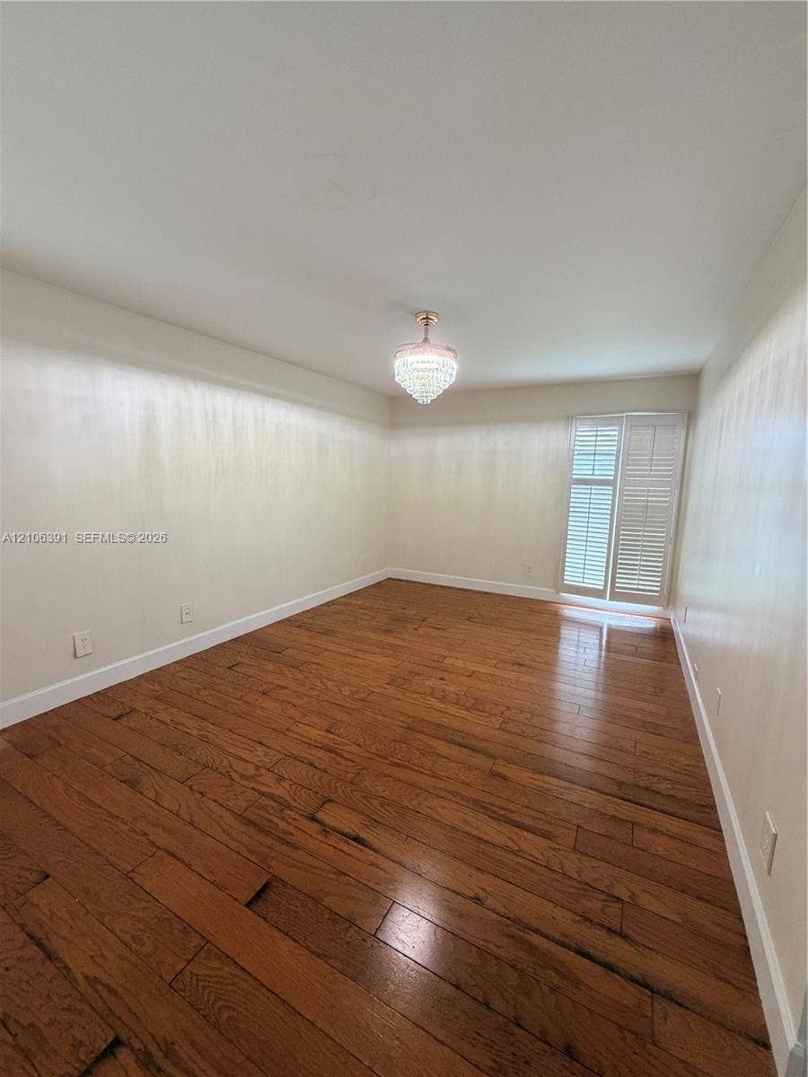 Room featuring wood-finish flooring, crystal-style pendant lighting, and louvered window shutters