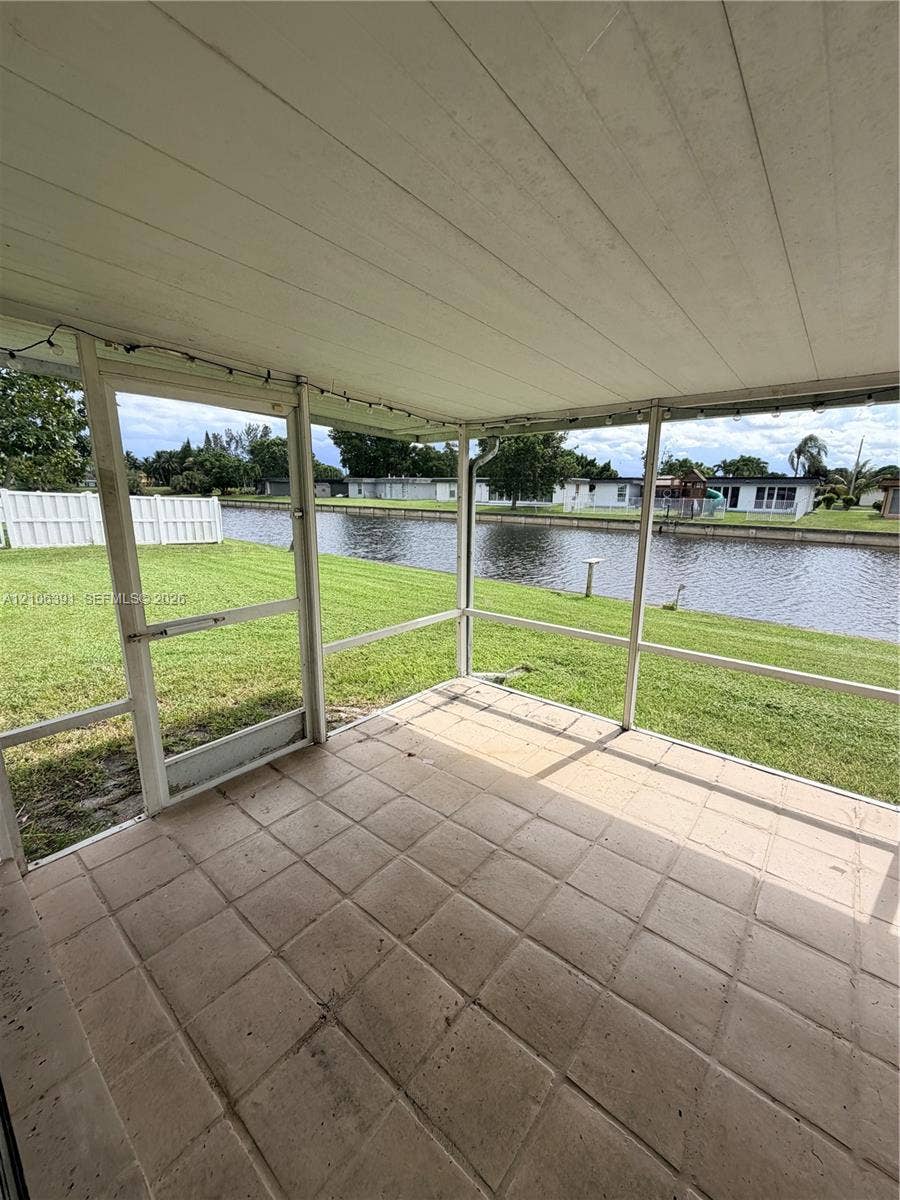 Screened-in porch with tile flooring, elevated ceiling, and direct water frontage