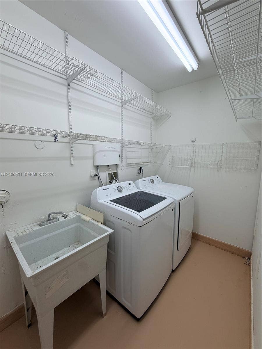 Utility room featuring a utility sink, built-in wire shelving, and overhead fluorescent lighting