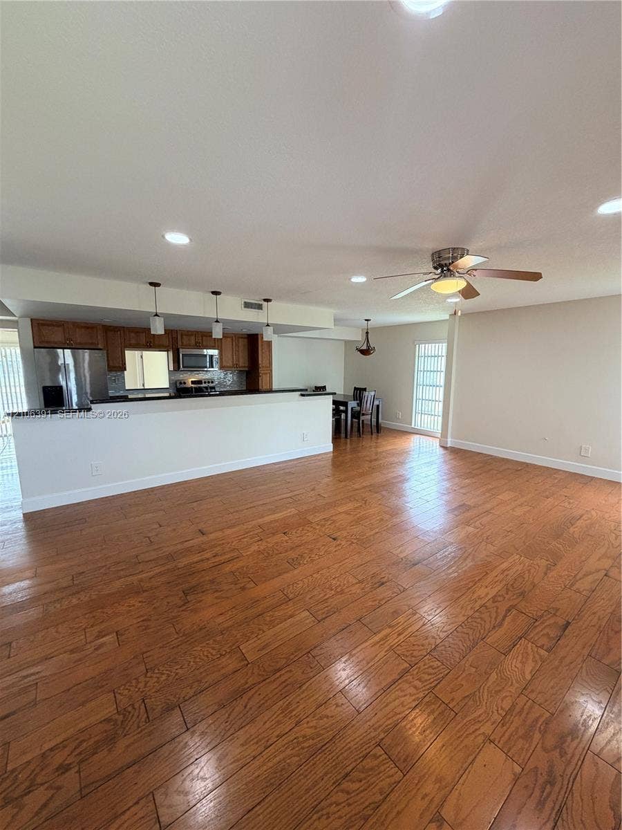 Open-concept kitchen featuring wood cabinetry, stainless steel appliances, and a breakfast bar