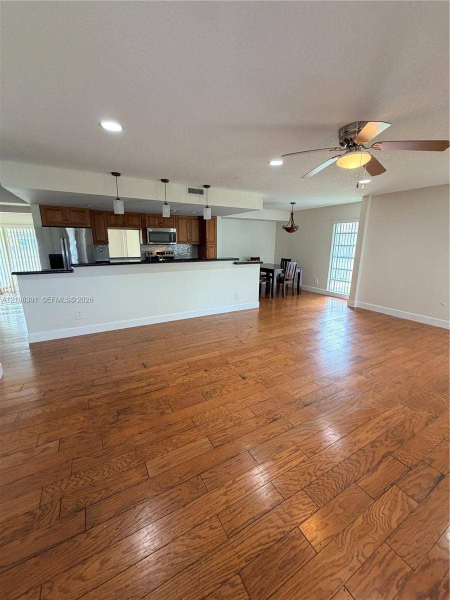 Wood-finish flooring, kitchen featuring a breakfast bar, recessed lighting, and a ceiling fan