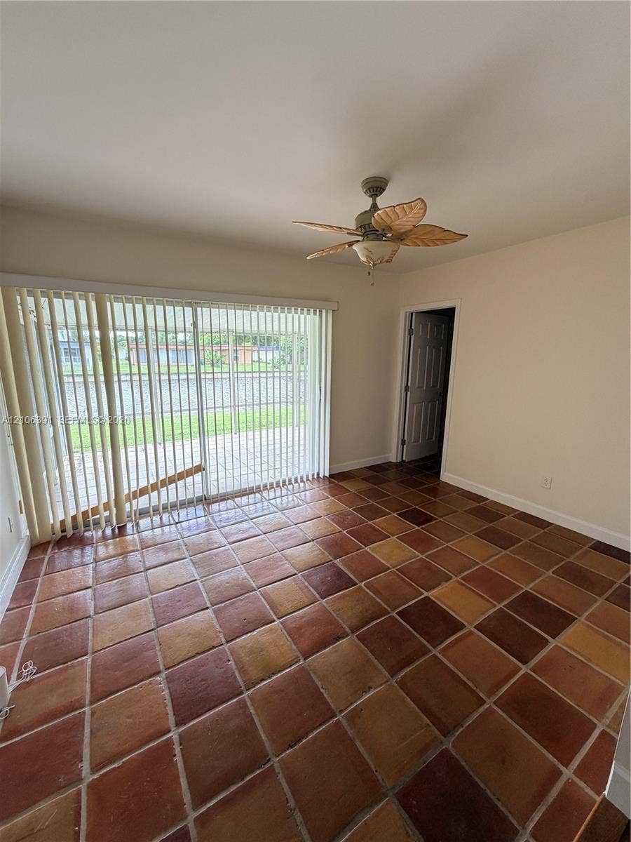 Interior space featuring multi-tonal ceramic tile flooring, sliding glass doors with vertical blinds, and a multi-blade ceiling fan