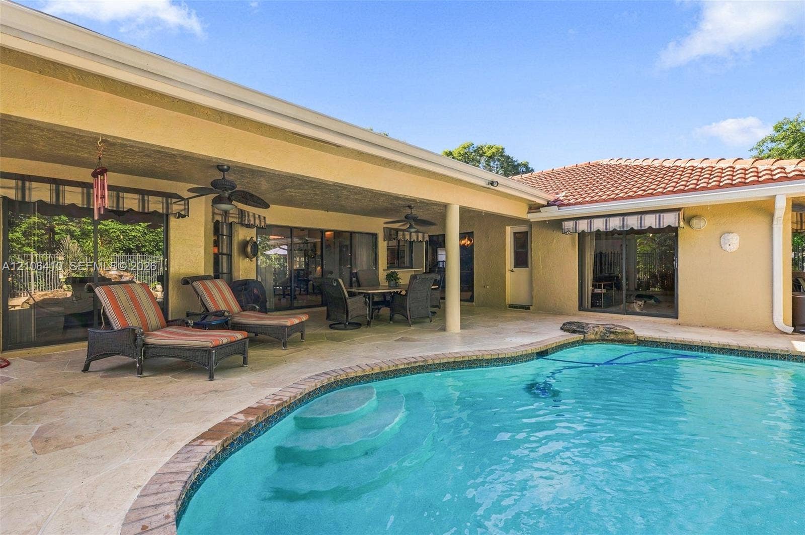 1725 Lakeshore Circle, Weston, FL 33326 Covered lanai featuring natural stone flooring, recessed ceiling fans, and an inground pool with tile surround
