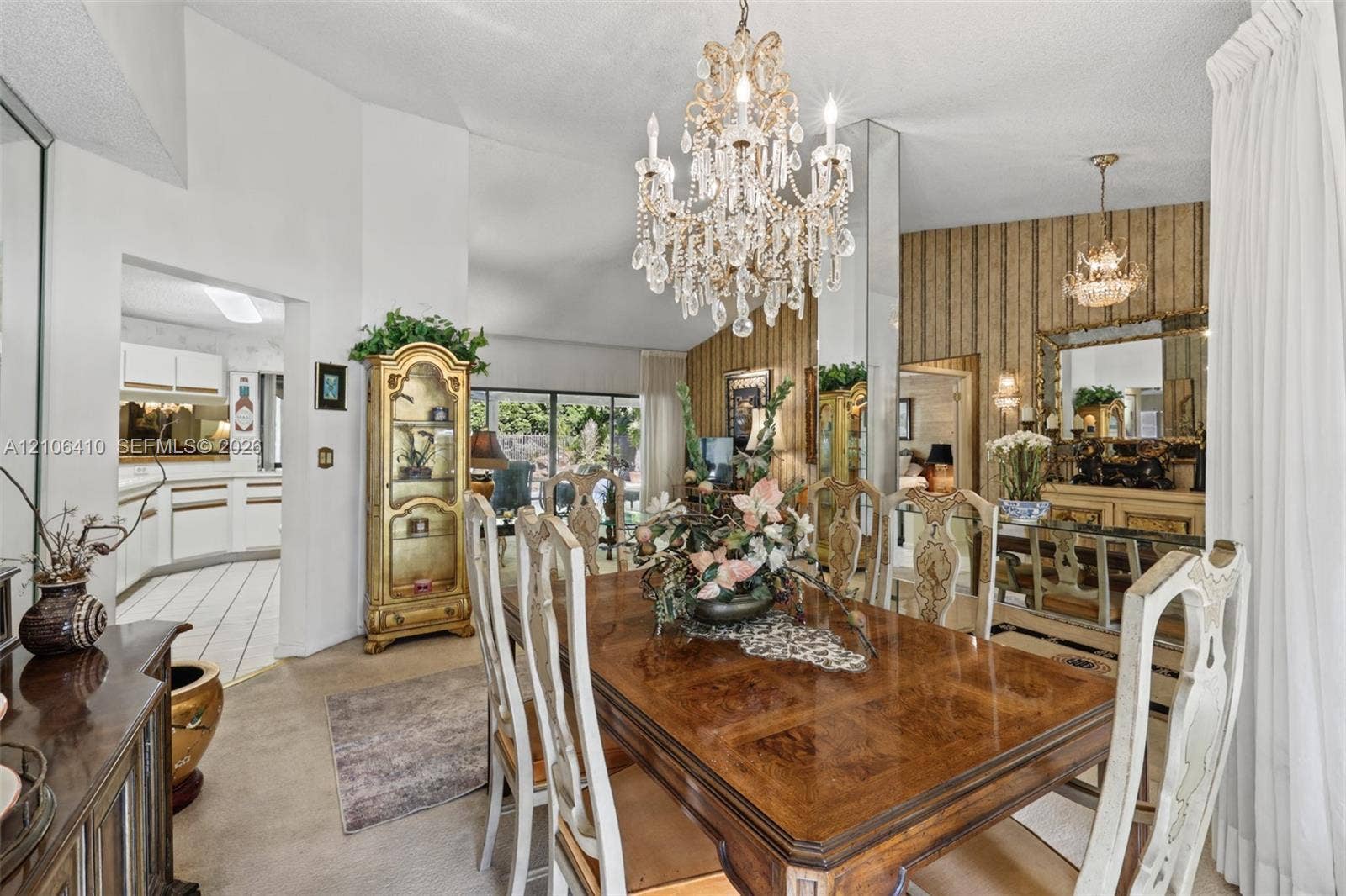 1725 Lakeshore Circle, Weston, FL 33326 Dining area featuring vaulted ceilings, a central crystal chandelier, floor-to-ceiling mirror paneling, and textured wallpaper