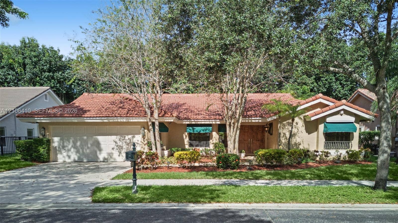 1725 Lakeshore Circle, Weston, FL 33326 Single-story exterior featuring a clay tile roof, stucco facade, double-door entry, and an attached two-car garage