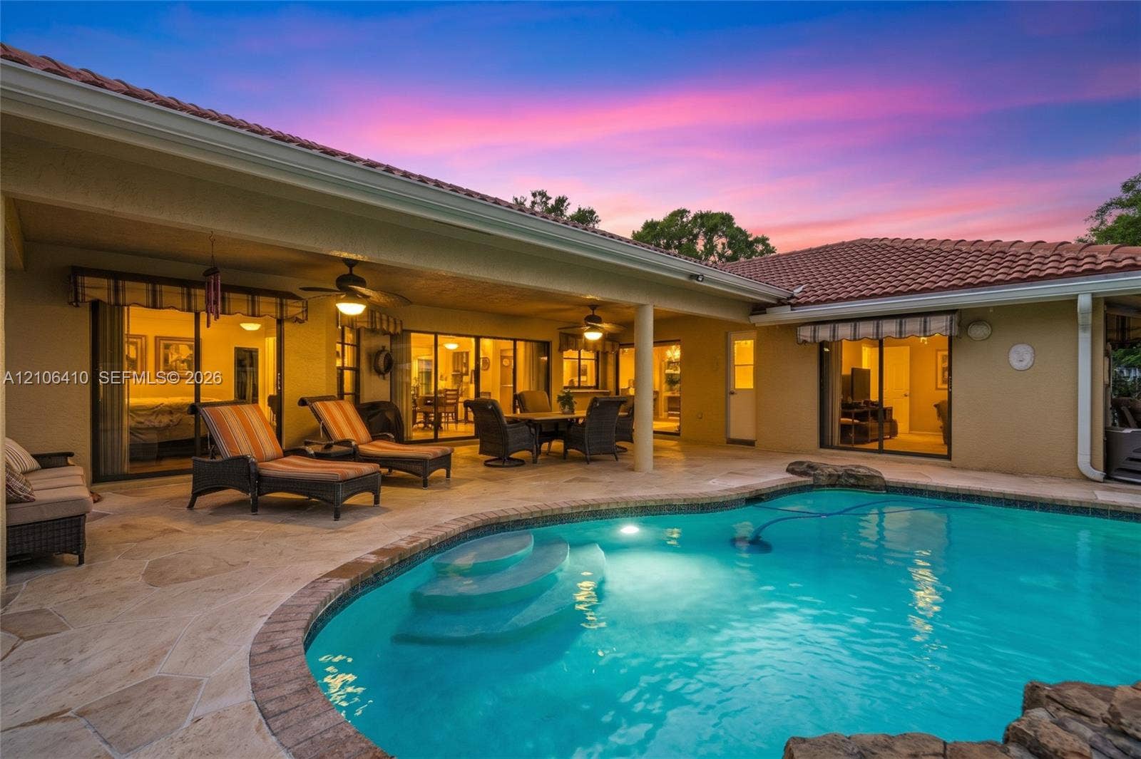 1725 Lakeshore Circle, Weston, FL 33326 Covered patio featuring stone-tiled flooring and dual ceiling fans, paired with an inground pool with built-in steps and rock-feature masonry
