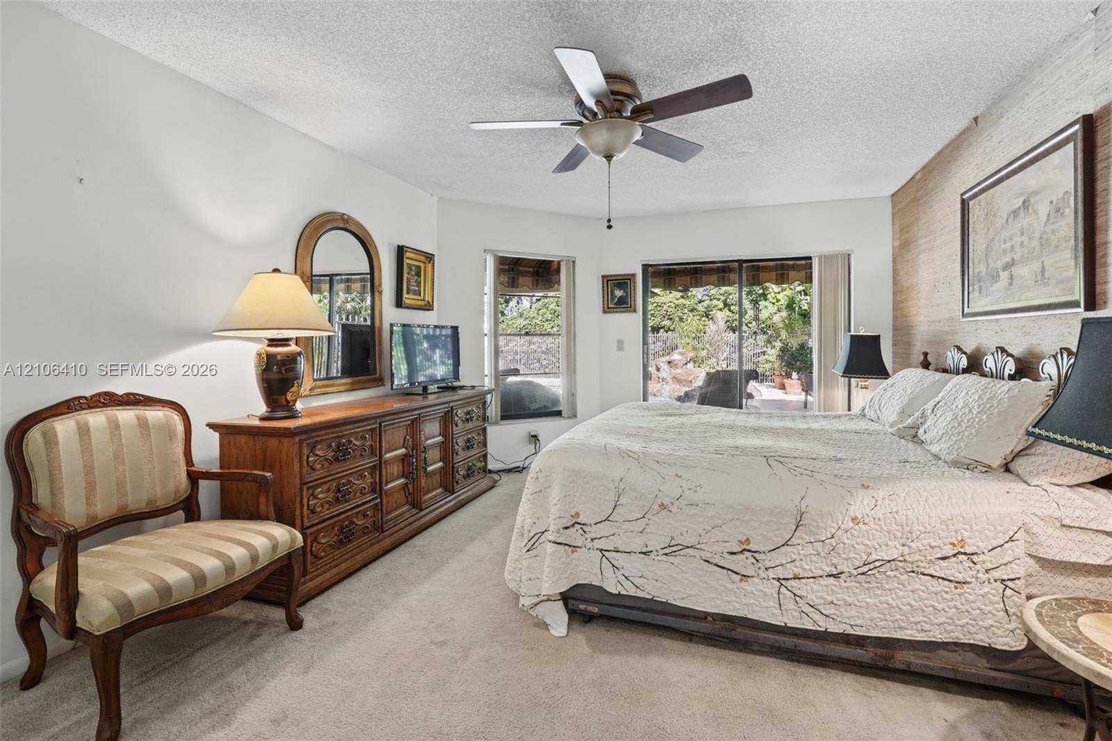 1725 Lakeshore Circle, Weston, FL 33326 Bedroom featuring an accent wall with natural-finish horizontal wood paneling, sliding glass doors, a corner window, and a ceiling fan