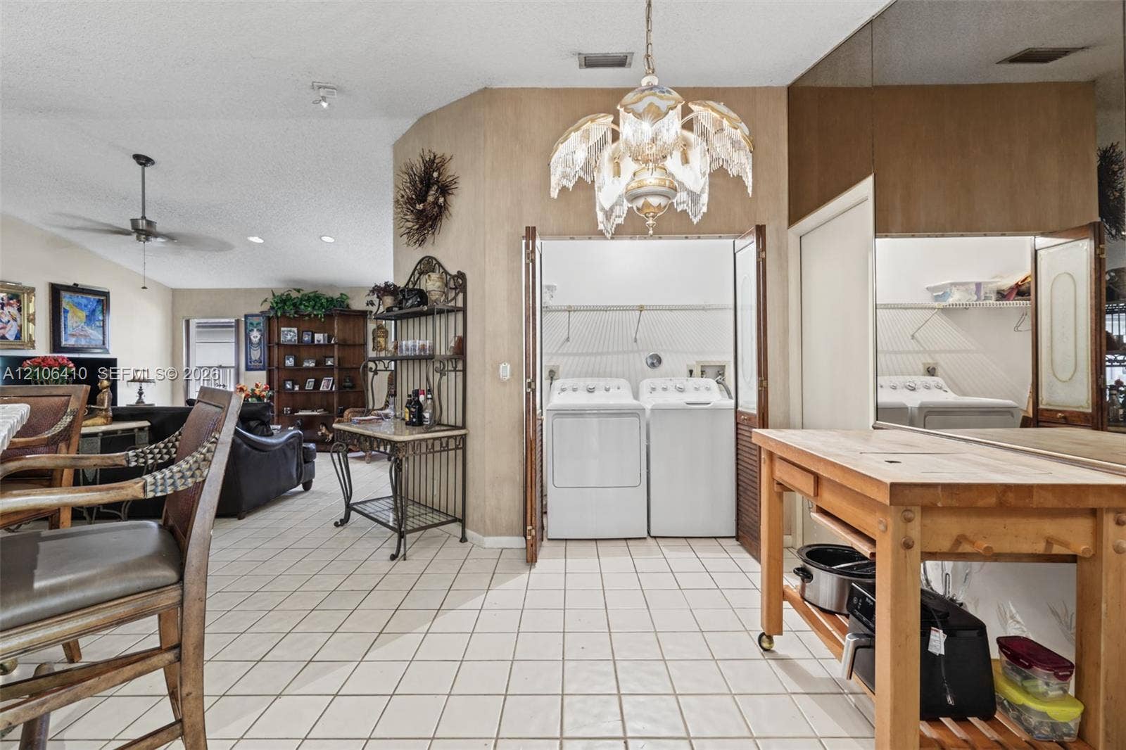 1725 Lakeshore Circle, Weston, FL 33326 Ceramic tile flooring, vaulted ceilings, and built-in laundry closet with bi-fold doors, accented by decorative chandelier lighting and mirrored wall paneling