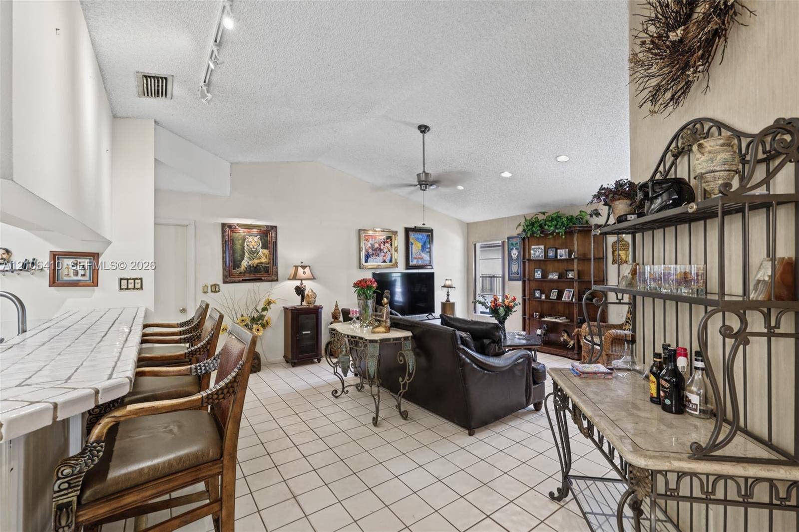 1725 Lakeshore Circle, Weston, FL 33326 Living area featuring vaulted ceilings, tile flooring, and a built-in kitchen peninsula with a tiled countertop and breakfast bar seating