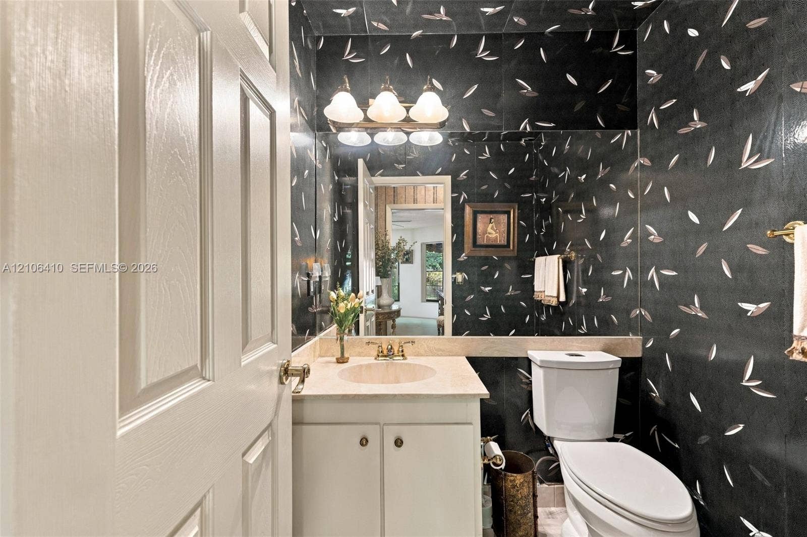 1725 Lakeshore Circle, Weston, FL 33326 Powder room featuring patterned wall covering, stone-finish countertop with an integrated basin, vanity cabinet with dual-door storage, full-width vanity mirror, and three-light wall-mounted fixture