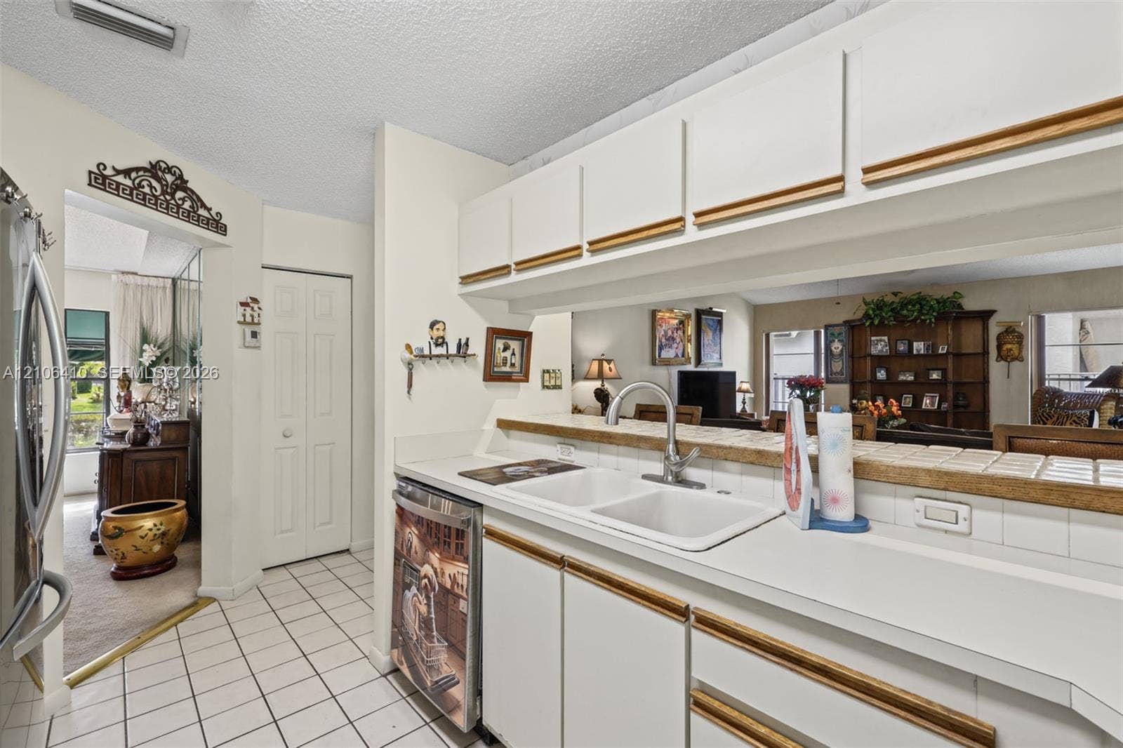 1725 Lakeshore Circle, Weston, FL 33326 Kitchen featuring white cabinetry with wood trim, white tile countertops, dual-basin sink, and ceramic tile flooring