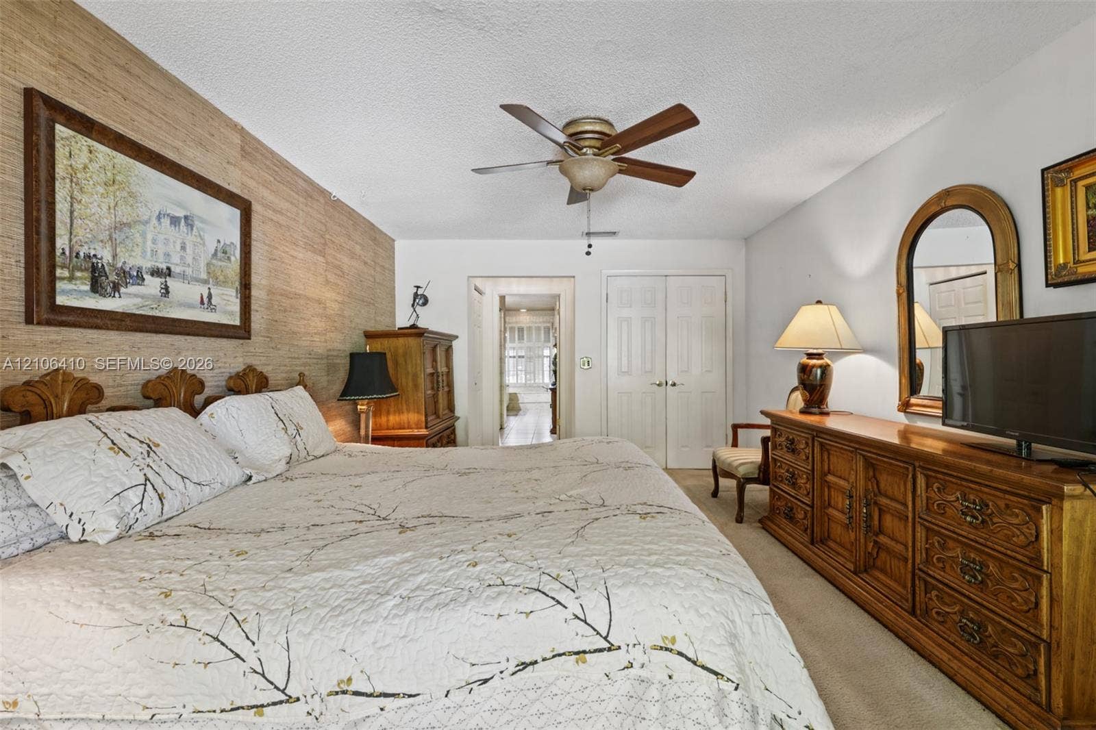 1725 Lakeshore Circle, Weston, FL 33326 Textured wood-toned accent wall, ceiling-mounted fan with integrated lighting, and dual-panel closet doors