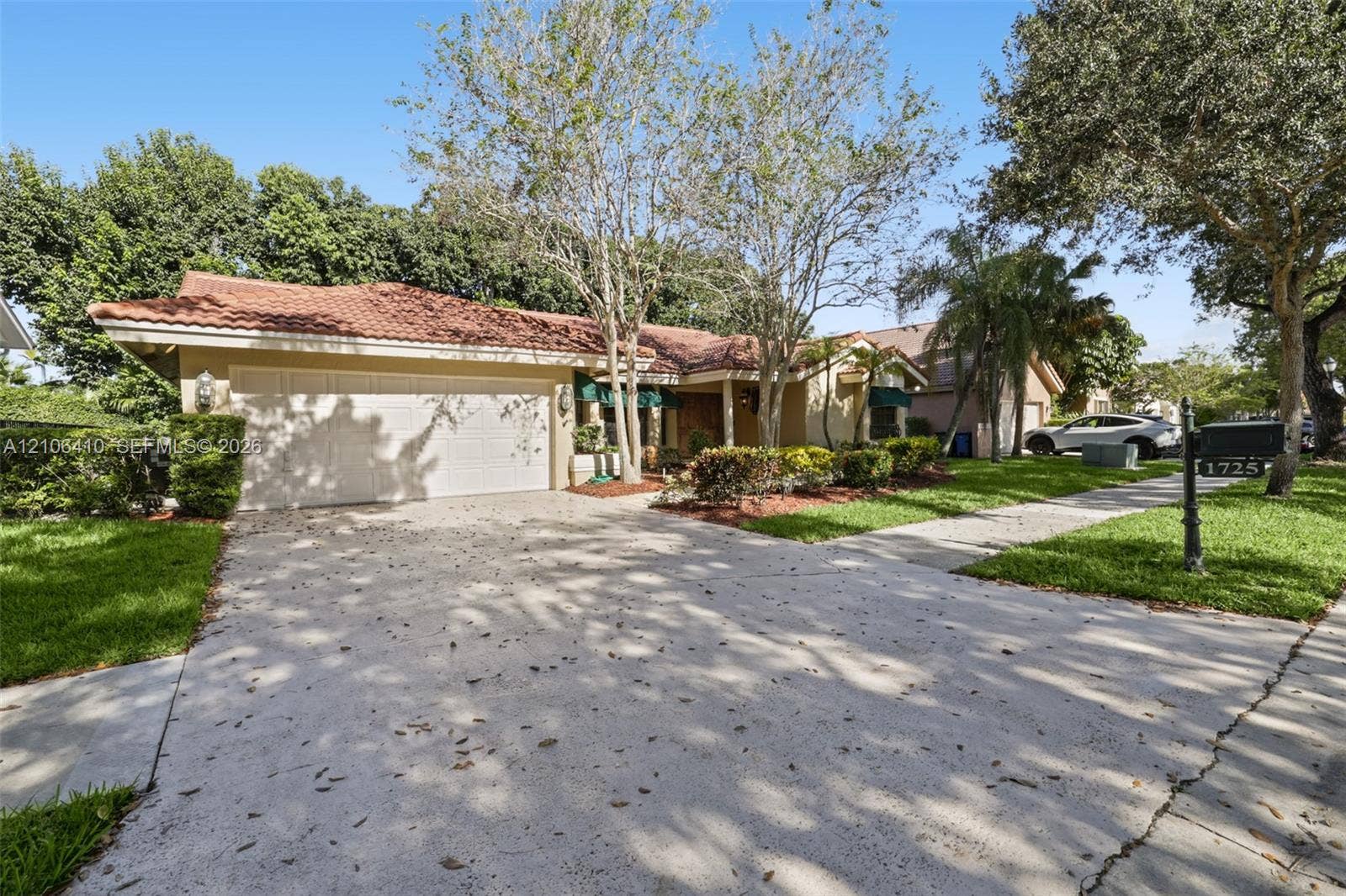 1725 Lakeshore Circle, Weston, FL 33326 Single-story residence featuring a tile roof, light-toned stucco exterior, and a multi-car garage with a concrete driveway