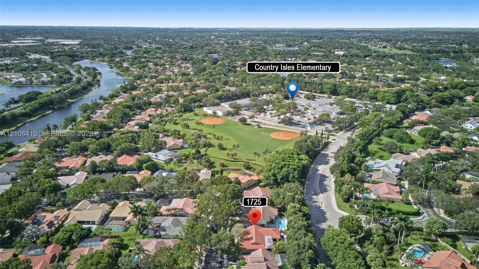 1725 Lakeshore Circle, Weston, FL 33326 Aerial perspective of residential property featuring a tiled roof, private swimming pool, mature canopy trees, and proximity to expansive green space and water frontage