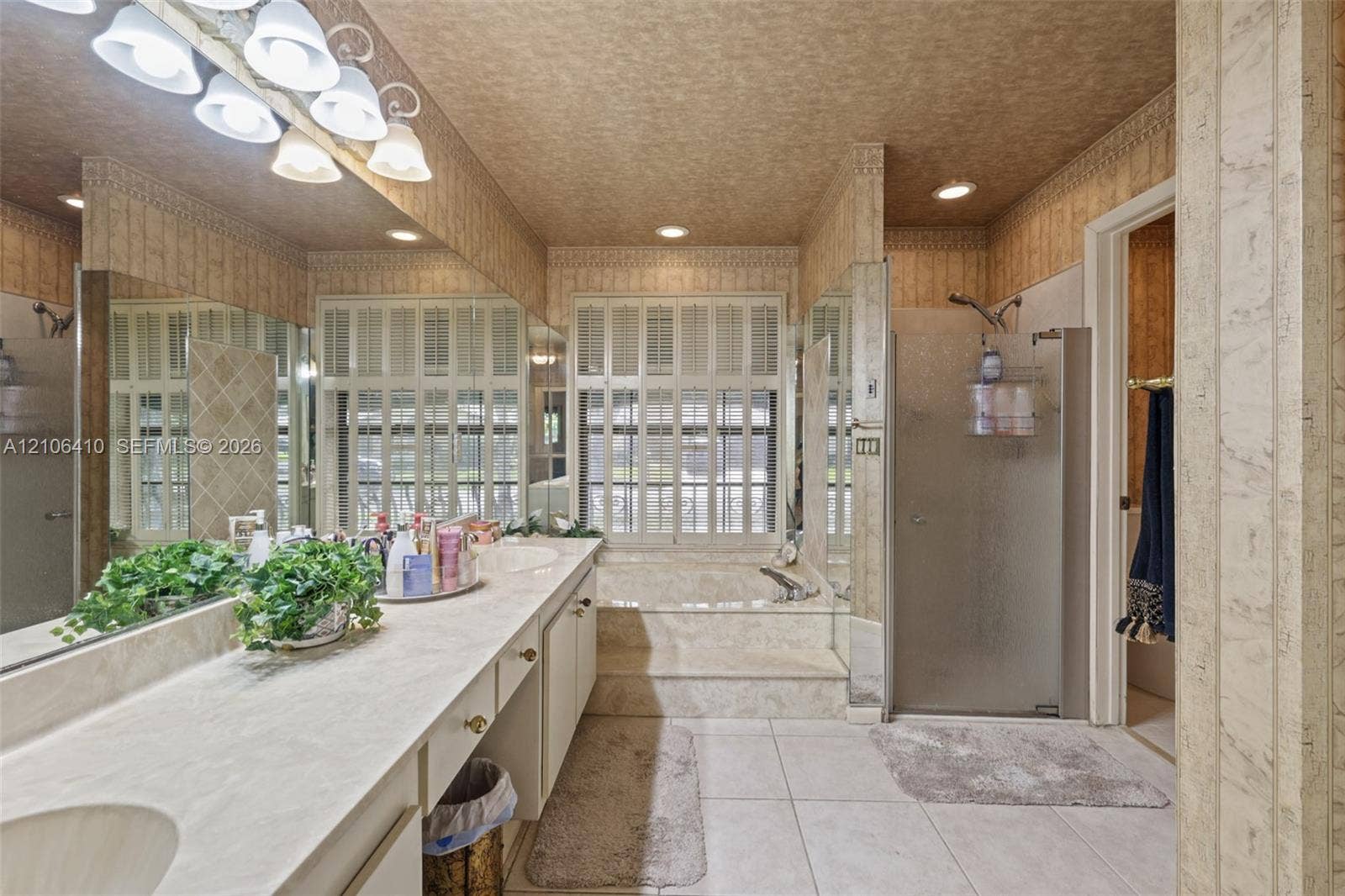 1725 Lakeshore Circle, Weston, FL 33326 Dual-sink vanity with integrated countertop, recessed lighting, glass-enclosed shower, built-in soaking tub with surround, and large-format tile flooring