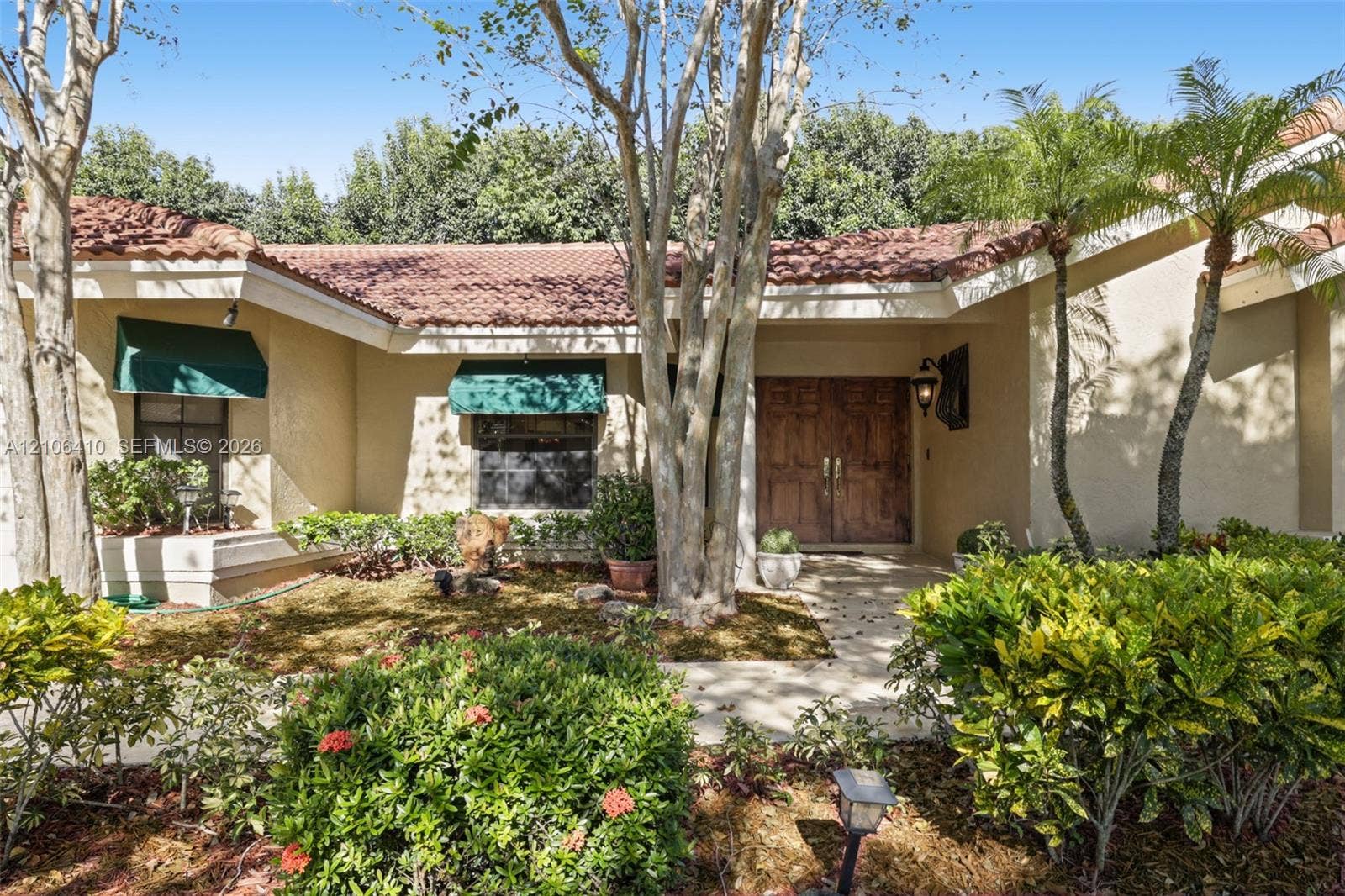1725 Lakeshore Circle, Weston, FL 33326 Stucco exterior featuring a clay tile roof, double-door entry, and decorative canvas window awnings