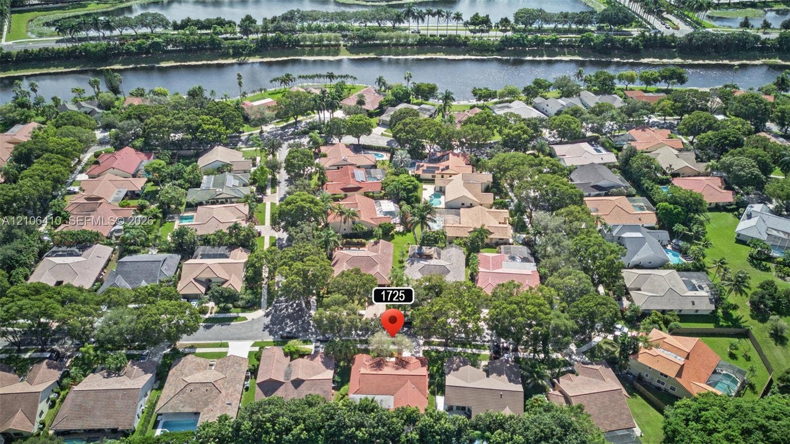 1725 Lakeshore Circle, Weston, FL 33326 Aerial perspective of residential neighborhood featuring mature canopy trees, paved street grid, and bordering waterway
