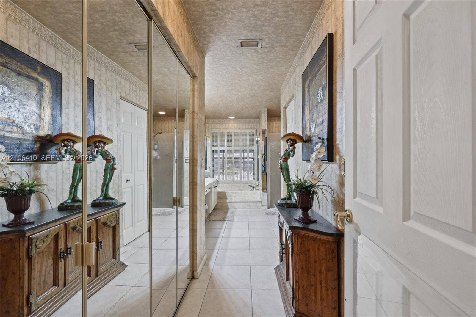 1725 Lakeshore Circle, Weston, FL 33326 Hallway featuring full-height mirrored closet doors, tile flooring, crown molding, and a multi-pane window