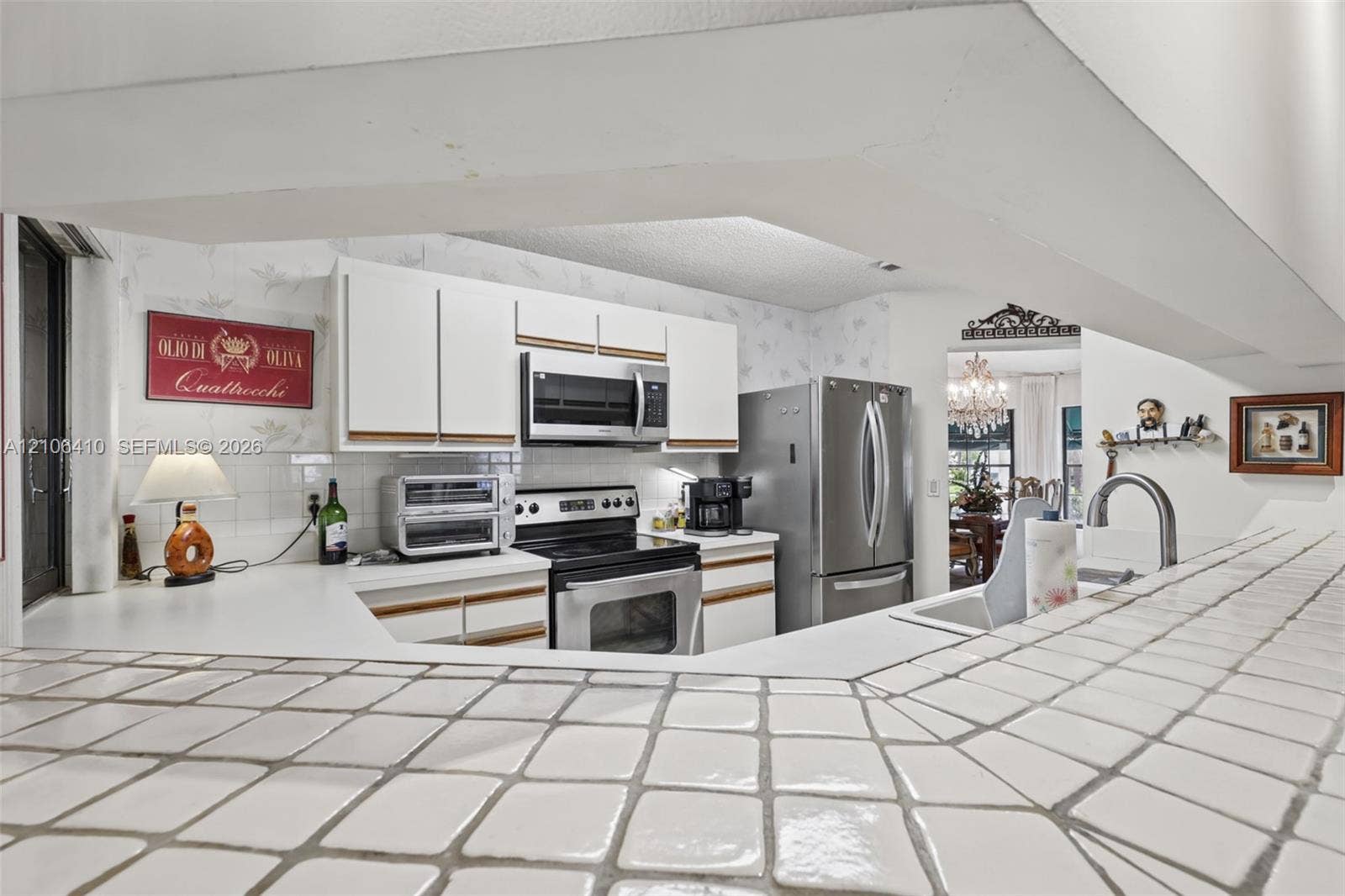 1725 Lakeshore Circle, Weston, FL 33326 Kitchen featuring white cabinetry, tiled countertop, stainless steel appliances, and a built-in kitchen sink with a gooseneck faucet