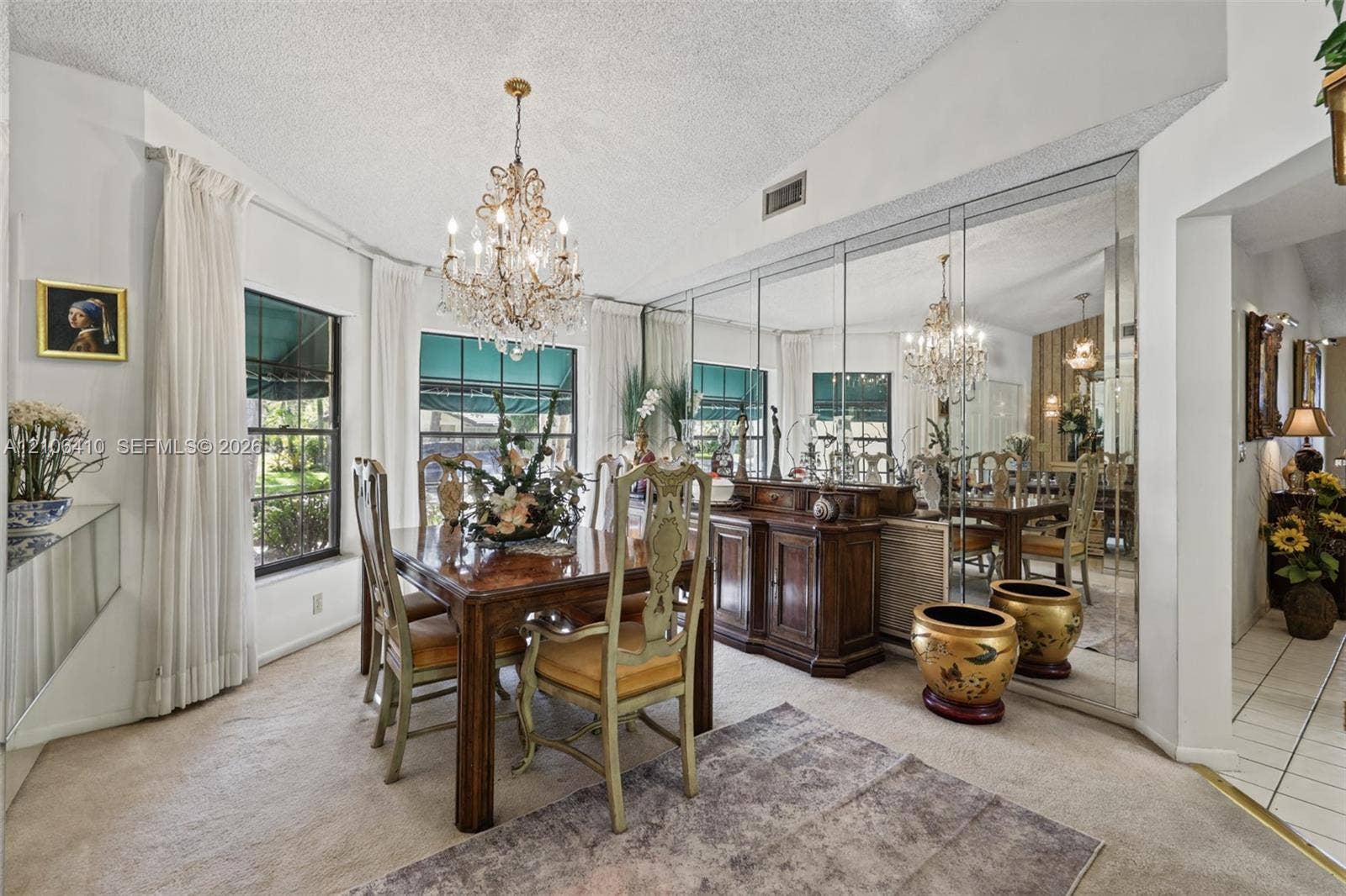 1725 Lakeshore Circle, Weston, FL 33326 Dining area featuring vaulted ceilings, a decorative crystal chandelier, and a wall-to-wall mirrored accent wall