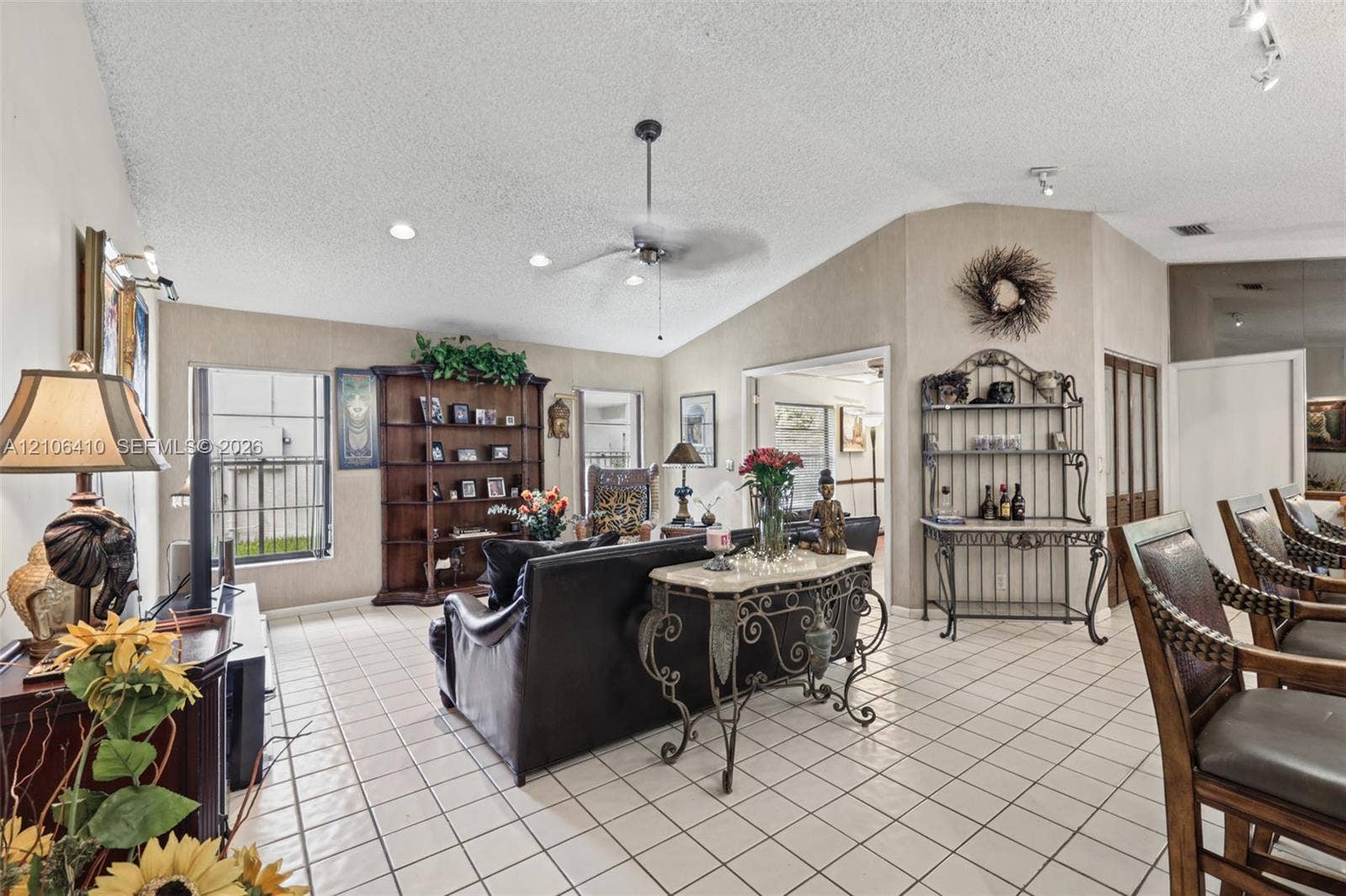 1725 Lakeshore Circle, Weston, FL 33326 Living area featuring vaulted ceilings, ceramic tile flooring, built-in shelving, and a central ceiling fan