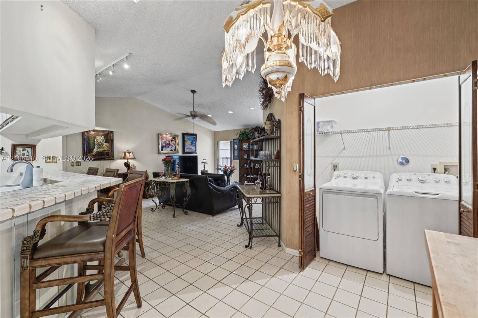 1725 Lakeshore Circle, Weston, FL 33326 Vaulted ceiling with decorative chandelier, tile flooring, and integrated laundry closet with bifold doors