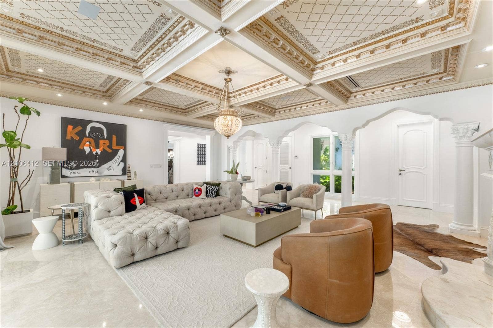 Coffered ceiling featuring intricate gold-leaf detailing, polished stone flooring, custom arched architectural columns, recessed lighting, and ornate hanging pendant light fixture