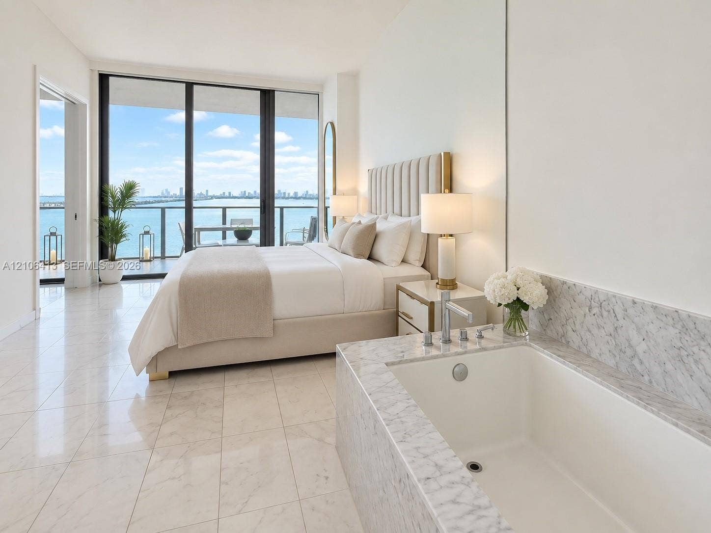 480 NE 31st Street, #1404, Miami, FL 33137 Floor-to-ceiling glass sliding doors, stone tile flooring, built-in soaking tub with stone surround, and balcony with metal railing