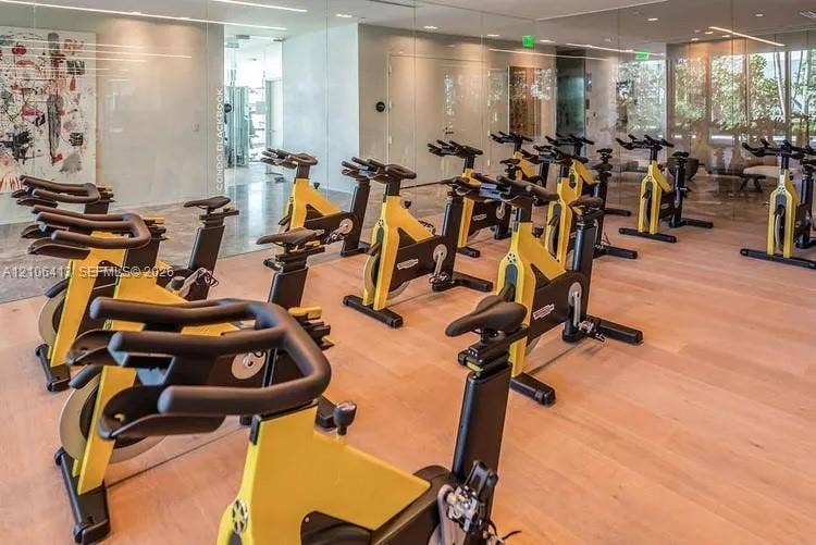 480 NE 31st Street, #1404, Miami, FL 33137 Fitness center featuring wood-finish flooring, floor-to-ceiling mirrored walls, and recessed linear lighting