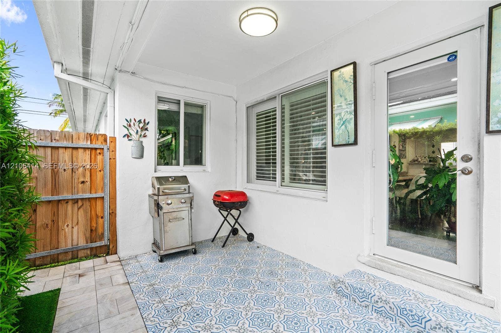 9133 Garland Avenue, Surfside, FL 33154 Covered patio featuring patterned tile flooring, a half-glass entry door, and white stucco walls